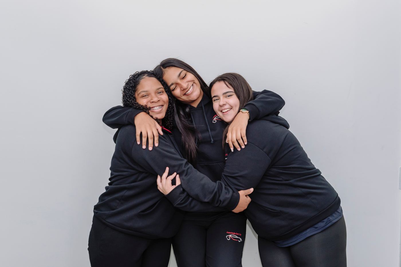 Três alunas da Associação Beni Car se abraçando e sorrindo
