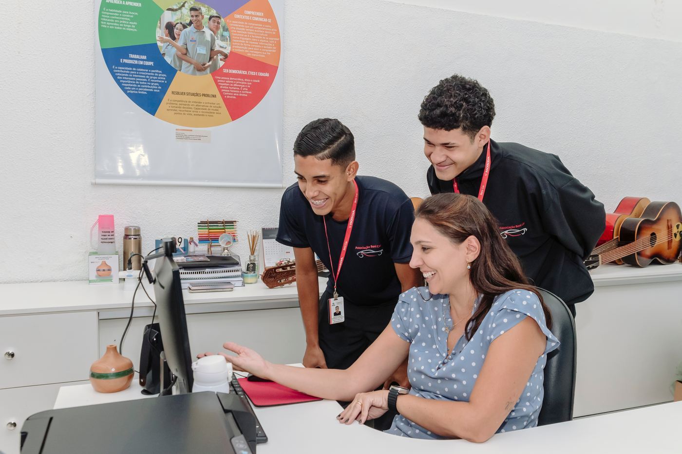 Aluno e educadora conversando em frente ao computador